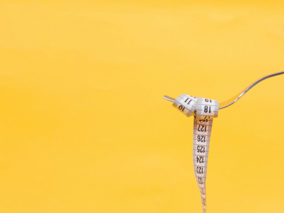 A fork with a measuring tape wrapped around it against a yellow background.