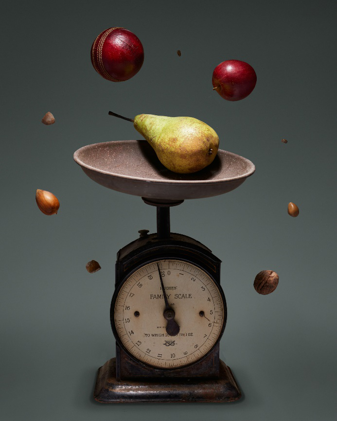 A vintage scale with pear and other fruits floating around, highlighting the importance of nutrient quality in calorie sources.