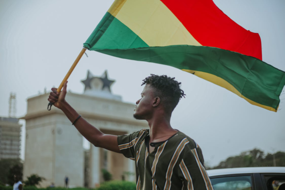 Man holding Ghana flag in front of historic landmark