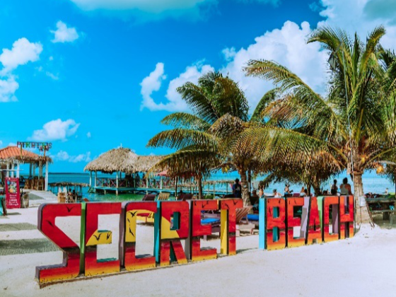 Colorful 'Secret Beach' sign at a vibrant beach location in Belize