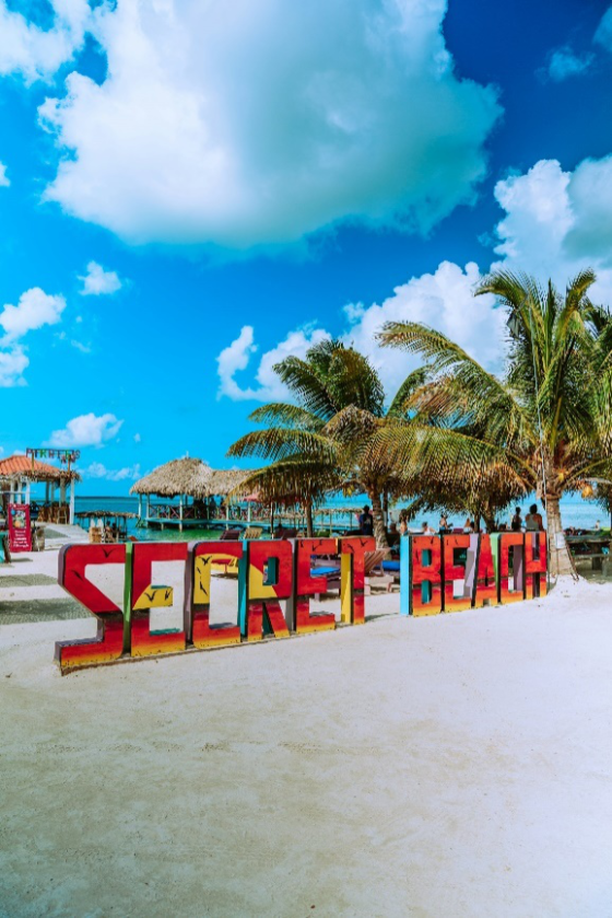 Colorful 'Secret Beach' sign at a vibrant beach location in Belize