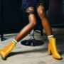 A woman wearing vibrant yellow boots, emphasizing bold fall fashion.