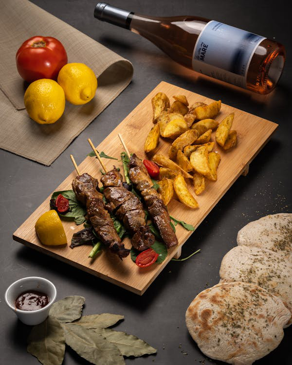 A traditional Greek dish of skewered meat, roasted potatoes, and pita bread with lemon garnish.