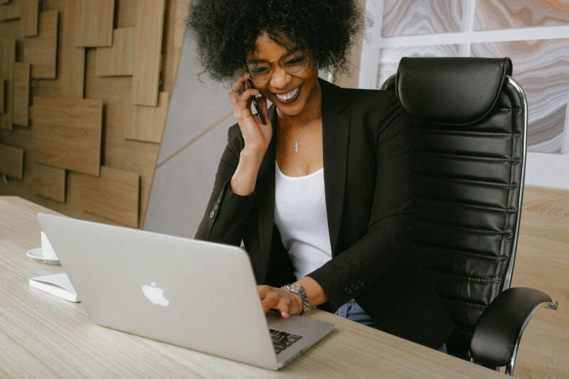 A woman laughing while working at her desk