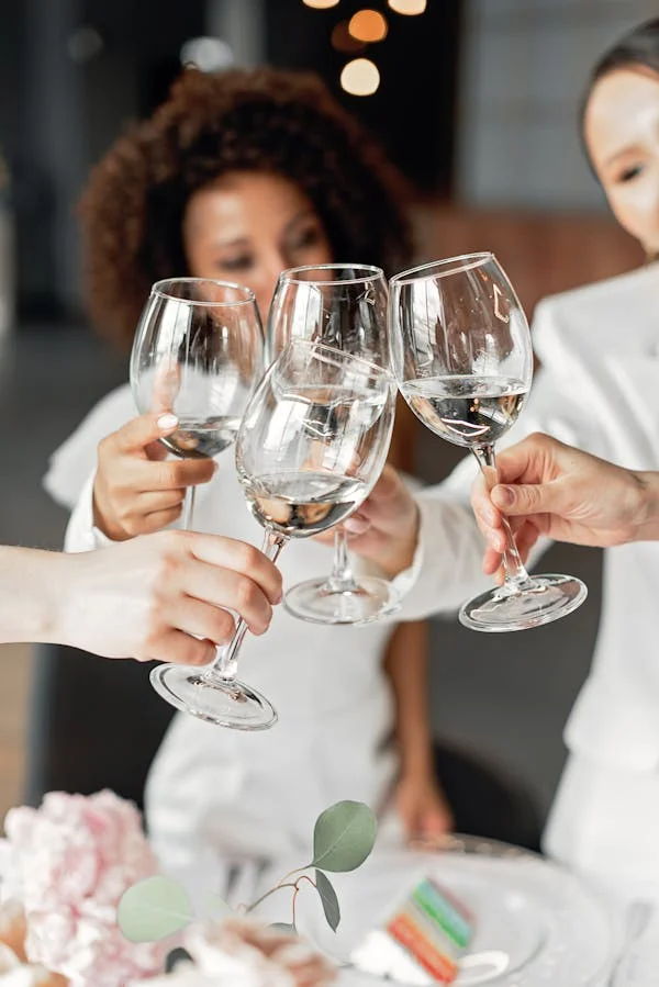 A group of women clinking their glasses of wine in celebration of Galentine’s Day.