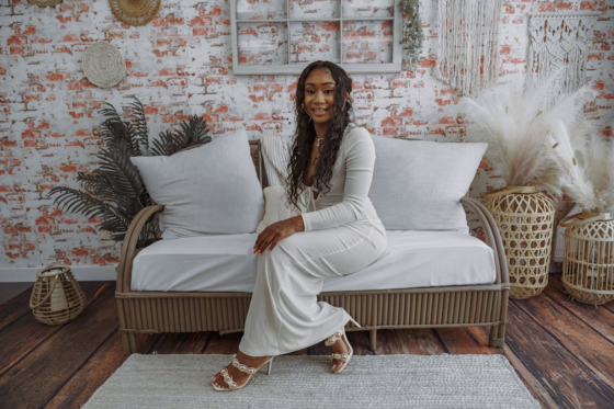 A stylish woman sitting in a beautifully decorated small living space with cozy accents.