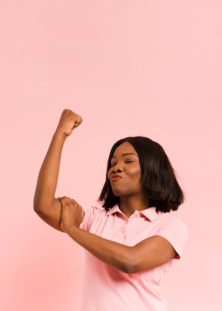 A woman flexing her arm in a pink shirt, representing strength and confidence.