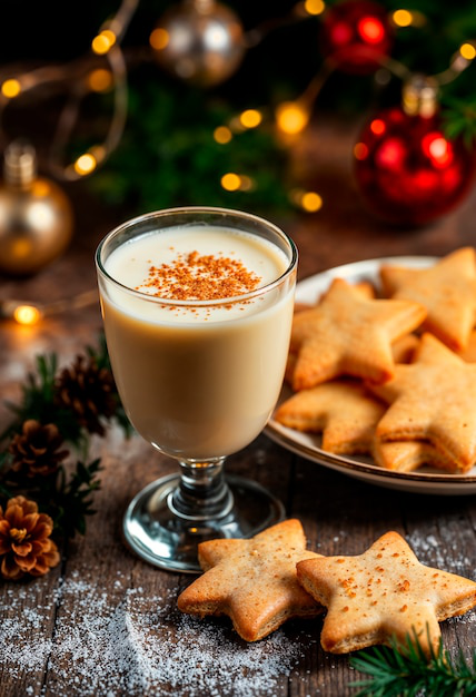Ponche de Creme in a glass next to star-shaped cookies.