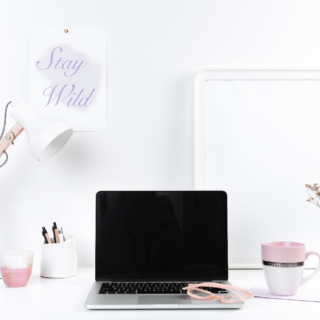 Minimalist home office setup with laptop, desk lamp, and pink coffee mug