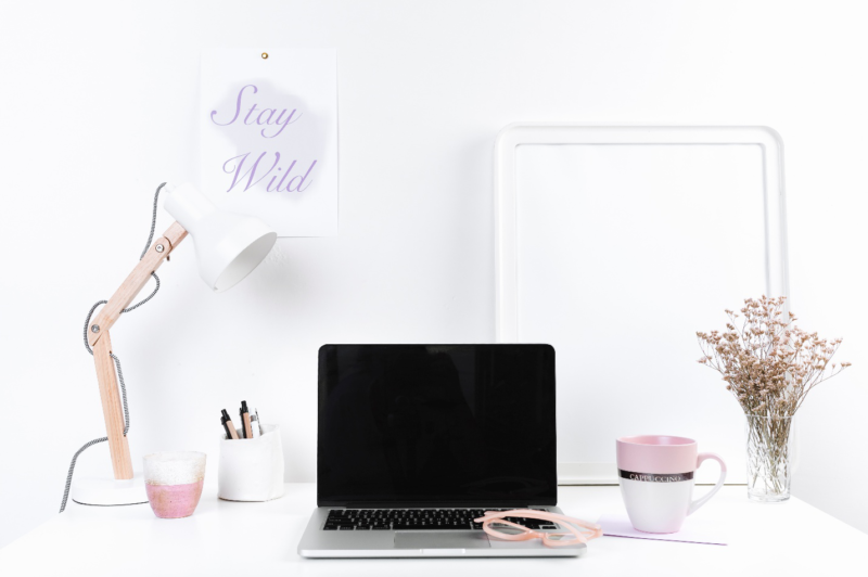 Minimalist home office setup with laptop, desk lamp, and pink coffee mug