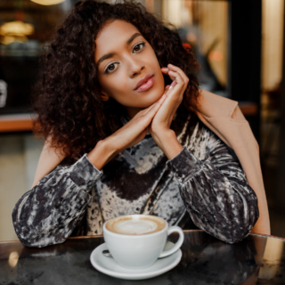 Confident young woman sitting at a café table with a cup of coffee