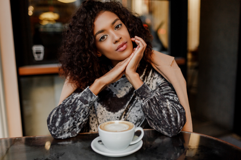 Confident young woman sitting at a café table with a cup of coffee