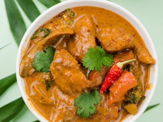 A bowl of Jamaican curry chicken with rice on a green background