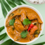 A bowl of Jamaican curry chicken with rice on a green background