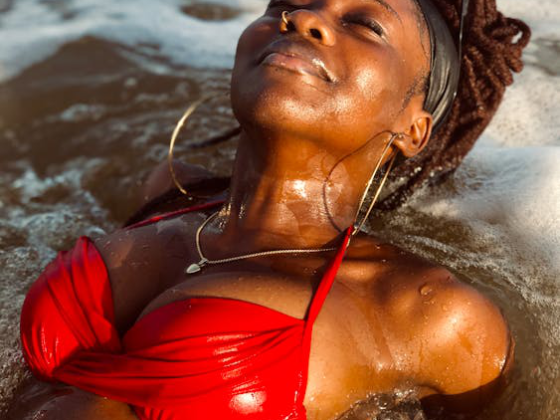 A woman relaxing in ocean water with eyes closed and glowing skin