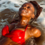 A woman relaxing in ocean water with eyes closed and glowing skin