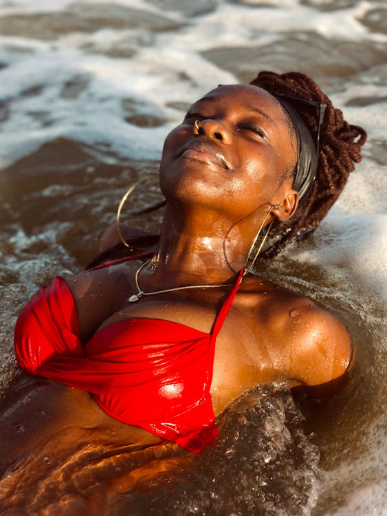 A woman relaxing in ocean water with eyes closed and glowing skin