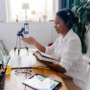 A woman wearing headphones in a remote work setup with a laptop and phone