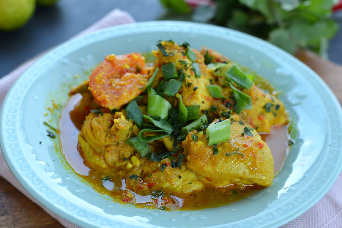 Yellow Jamaican curry chicken garnished with scallions and tomatoes