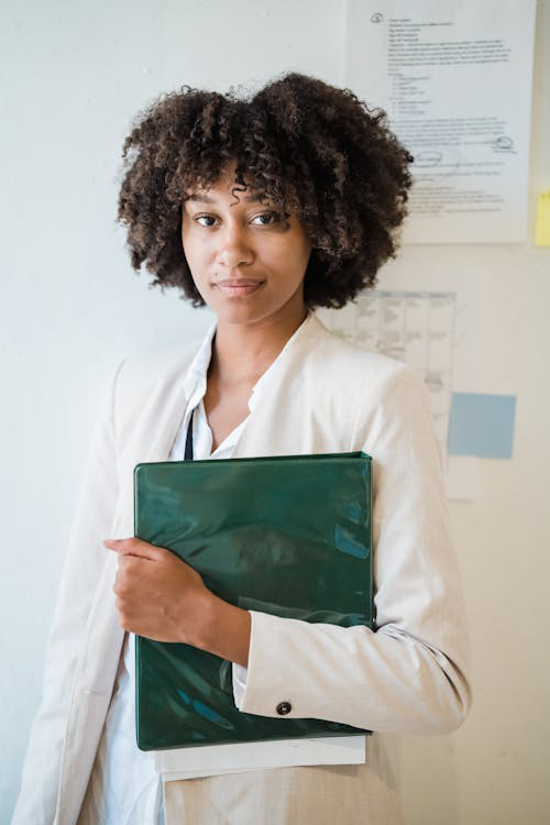 A woman in a white blazer holding a binder